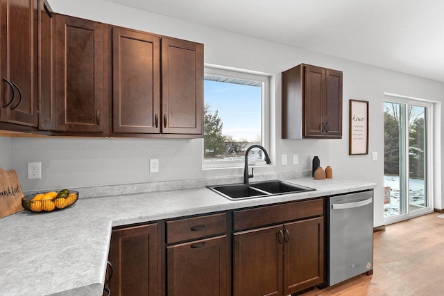 kitchen with dark brown cabinetry, dishwasher, sink, and light wood-type flooring