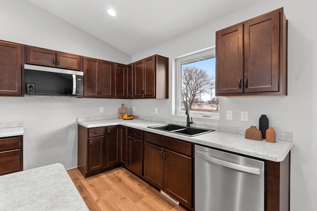 kitchen with lofted ceiling, sink, dark brown cabinets, light wood-type flooring, and appliances with stainless steel finishes