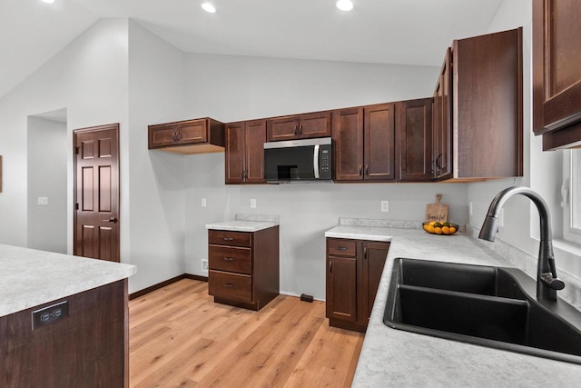 kitchen with high vaulted ceiling, light hardwood / wood-style floors, and sink