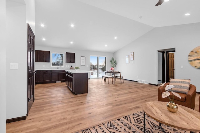 interior space featuring lofted ceiling, dark brown cabinets, a kitchen island, ceiling fan, and light hardwood / wood-style floors