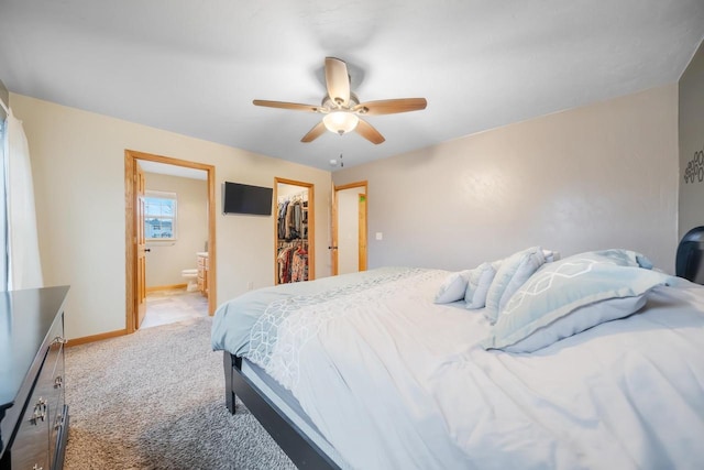 bedroom featuring ensuite bath, ceiling fan, light carpet, a walk in closet, and a closet