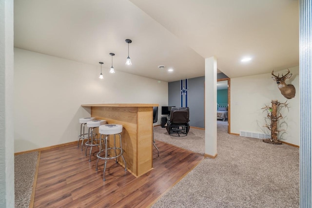 bar featuring hanging light fixtures, dark hardwood / wood-style floors, and a wood stove