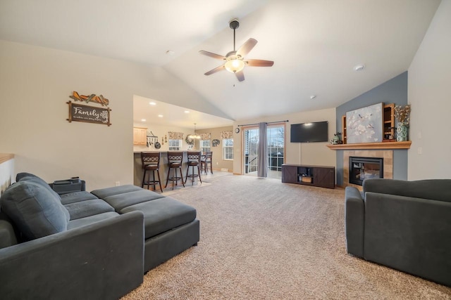 living room featuring ceiling fan, high vaulted ceiling, carpet flooring, a fireplace, and indoor bar