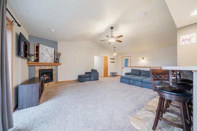 carpeted living room featuring a tiled fireplace, lofted ceiling, and ceiling fan