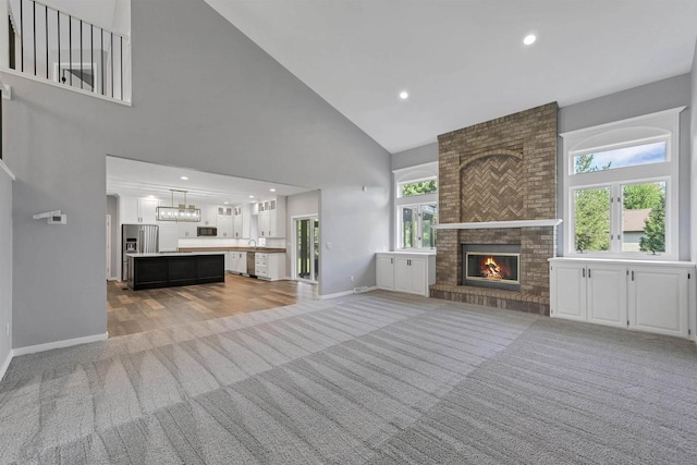 unfurnished living room featuring high vaulted ceiling, plenty of natural light, light carpet, and a fireplace