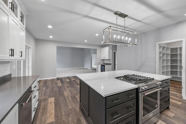 kitchen with white cabinetry, a center island, hanging light fixtures, appliances with stainless steel finishes, and dark hardwood / wood-style flooring