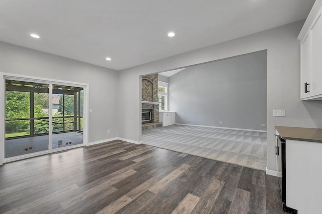 unfurnished living room with dark hardwood / wood-style floors and a stone fireplace