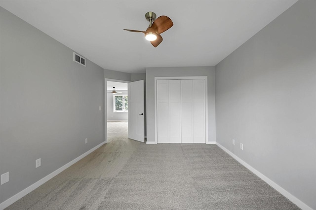 unfurnished bedroom featuring light carpet, a closet, and ceiling fan