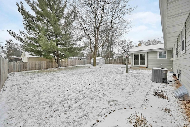 yard covered in snow with cooling unit and a storage unit