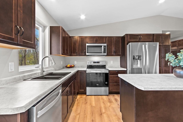 kitchen featuring sink, appliances with stainless steel finishes, dark brown cabinetry, light hardwood / wood-style floors, and vaulted ceiling