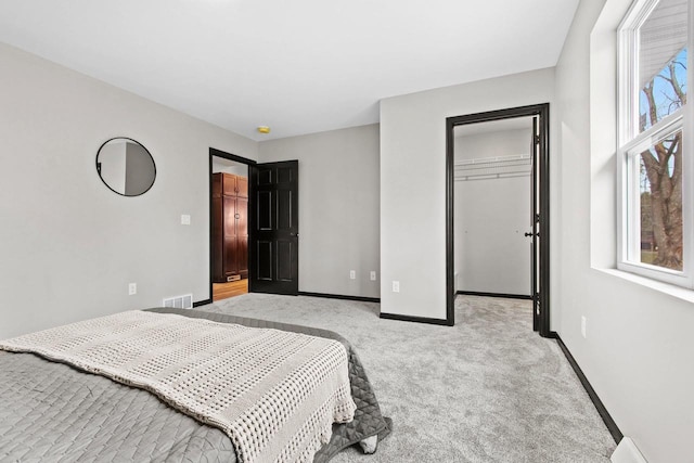 carpeted bedroom with a walk in closet and a closet