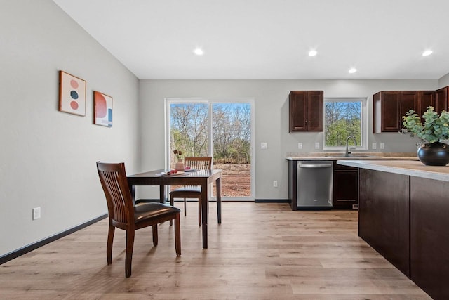 kitchen with sink, dark brown cabinets, stainless steel dishwasher, and light wood-type flooring