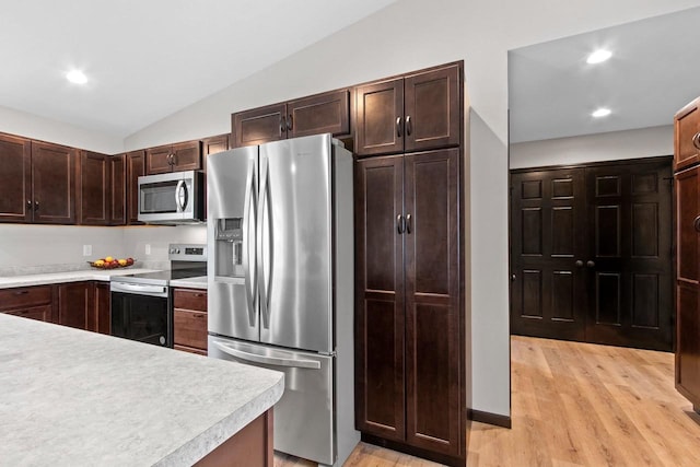 kitchen featuring stainless steel appliances, vaulted ceiling, dark brown cabinets, and light hardwood / wood-style flooring