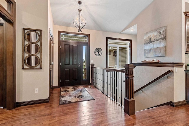 entryway with lofted ceiling, wood-type flooring, and a chandelier