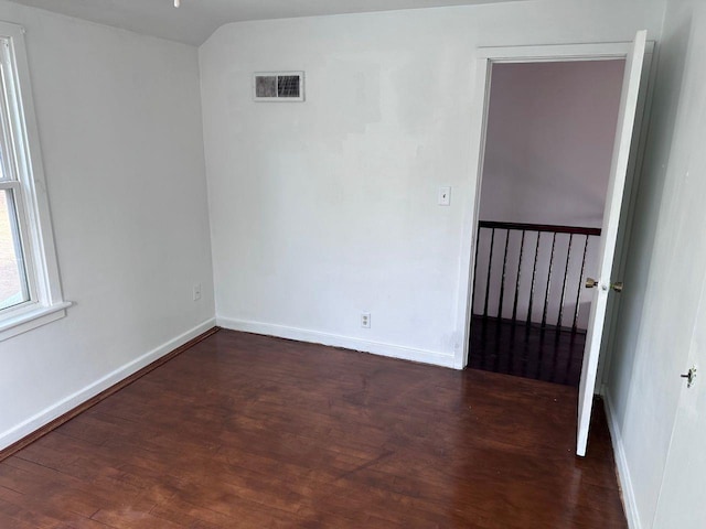 empty room with dark hardwood / wood-style flooring and lofted ceiling