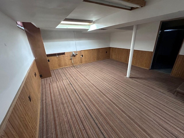 basement featuring carpet floors and wood walls