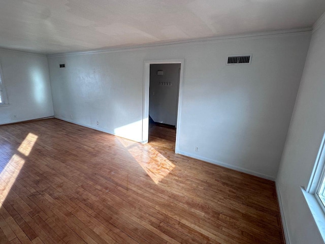 empty room featuring crown molding and hardwood / wood-style flooring