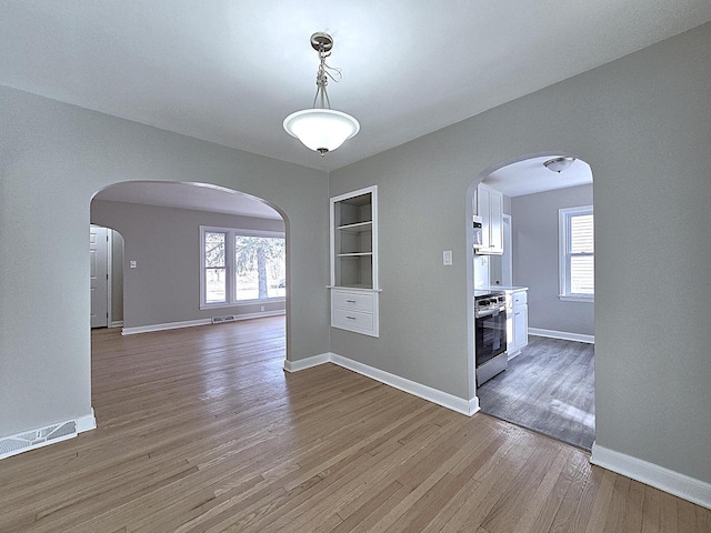 unfurnished dining area featuring hardwood / wood-style flooring, built in features, and a wealth of natural light