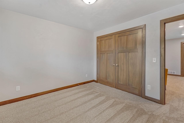 unfurnished bedroom with light colored carpet and a closet