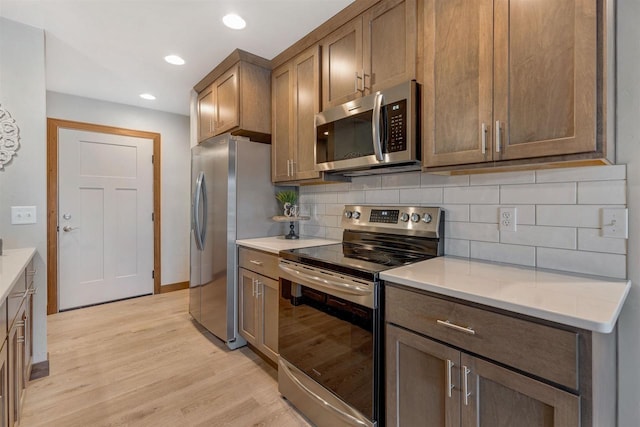 kitchen featuring decorative backsplash, stainless steel appliances, and light hardwood / wood-style flooring