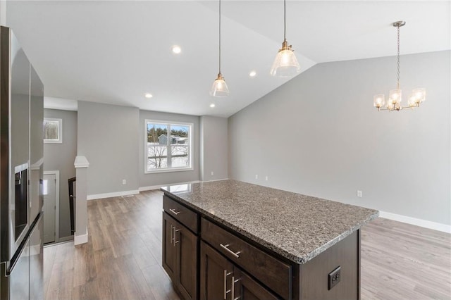 kitchen featuring dark brown cabinetry, vaulted ceiling, a center island, and light wood-type flooring