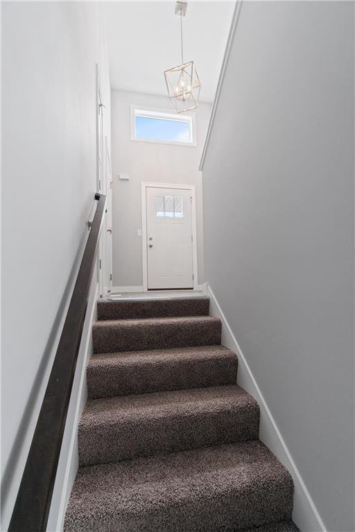 stairway featuring a chandelier