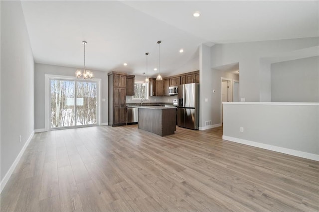 kitchen featuring appliances with stainless steel finishes, pendant lighting, a center island, a notable chandelier, and light hardwood / wood-style floors