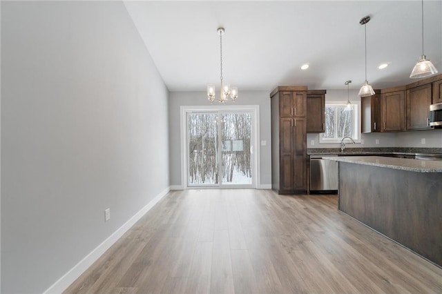 kitchen with appliances with stainless steel finishes, sink, a chandelier, hanging light fixtures, and light hardwood / wood-style flooring