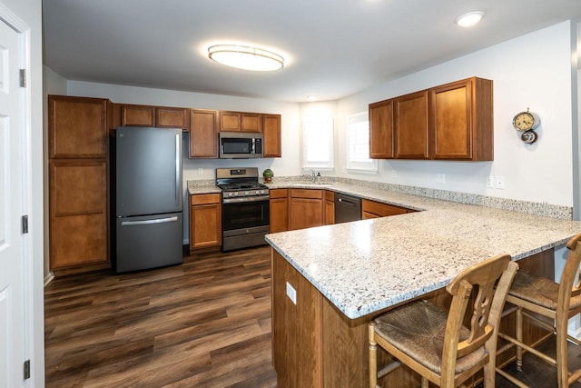 kitchen featuring sink, dark wood-type flooring, kitchen peninsula, and appliances with stainless steel finishes