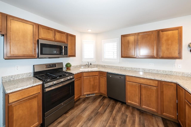 kitchen with dark hardwood / wood-style flooring, sink, light stone counters, and stainless steel appliances