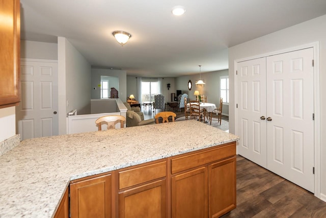 kitchen featuring light stone countertops, dark wood-type flooring, and pendant lighting