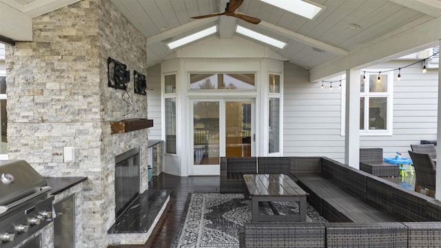 view of patio with ceiling fan, area for grilling, a grill, and an outdoor living space with a fireplace