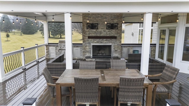 deck with an outdoor kitchen and an outdoor stone fireplace