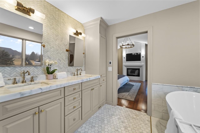 bathroom with tile walls, vanity, a bathing tub, and an inviting chandelier