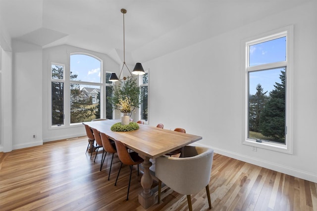 dining space featuring vaulted ceiling, light hardwood / wood-style floors, and a notable chandelier