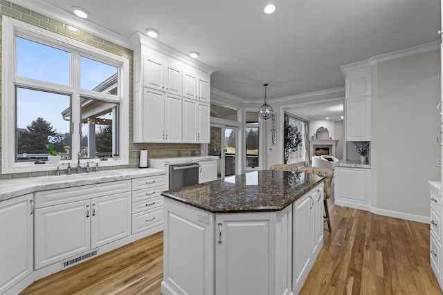 kitchen featuring white cabinetry, dark stone counters, a center island, and sink