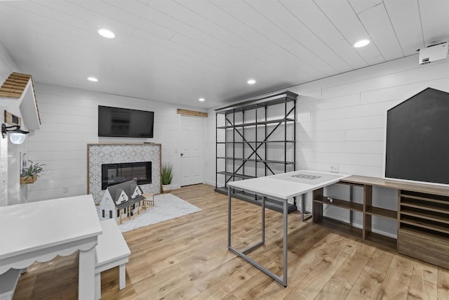 rec room with wooden walls, wooden ceiling, a fireplace, and light hardwood / wood-style flooring