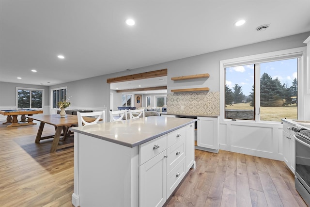 kitchen with backsplash, a kitchen island, light hardwood / wood-style flooring, and white cabinets