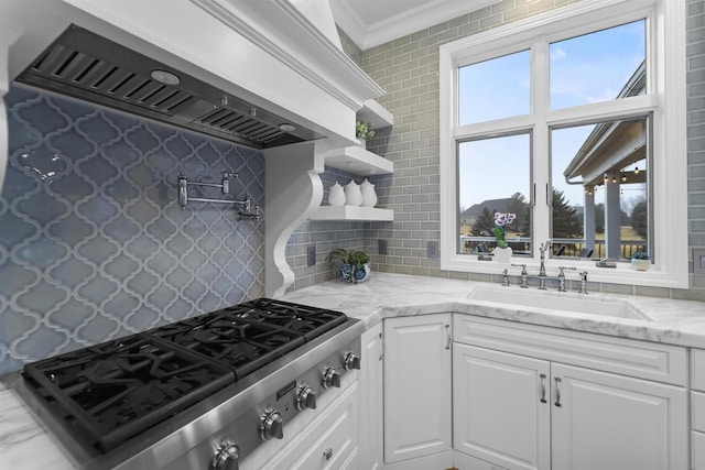 kitchen featuring premium range hood, sink, stainless steel gas cooktop, and white cabinets