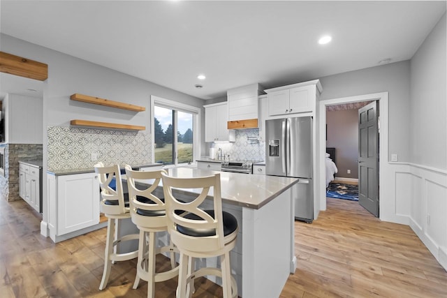 kitchen featuring a breakfast bar area, a kitchen island, stainless steel appliances, light hardwood / wood-style floors, and white cabinets