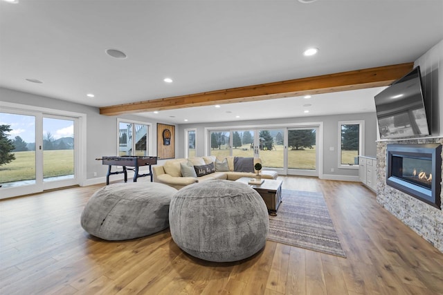 living room featuring light wood-type flooring, a wealth of natural light, and beam ceiling