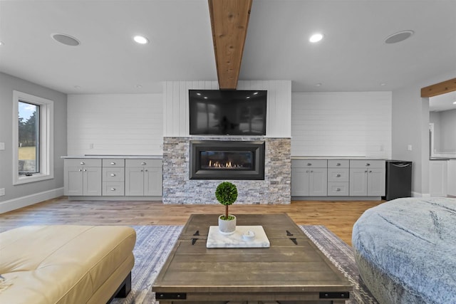 living room featuring beamed ceiling and light hardwood / wood-style flooring