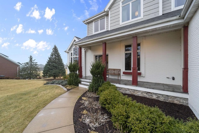 doorway to property with a lawn and a porch