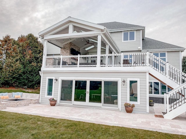 back of property with a balcony, a yard, ceiling fan, an outdoor fire pit, and a patio area