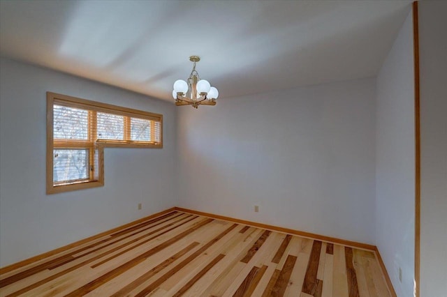 empty room with a notable chandelier and wood-type flooring