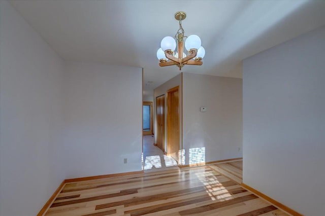 empty room with an inviting chandelier and light hardwood / wood-style floors