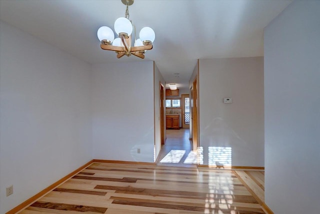 unfurnished room with a chandelier and light hardwood / wood-style floors