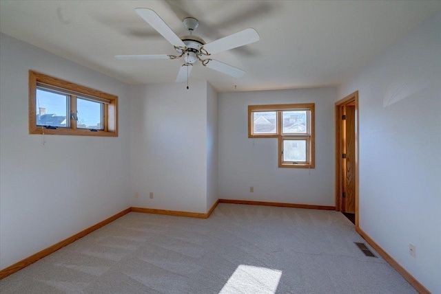 empty room featuring a healthy amount of sunlight, light carpet, and ceiling fan