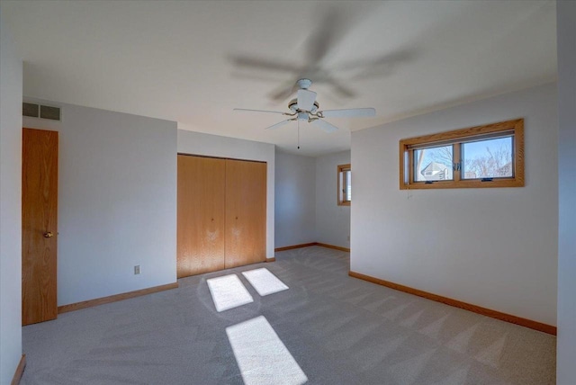 unfurnished bedroom with light colored carpet, ceiling fan, and a closet