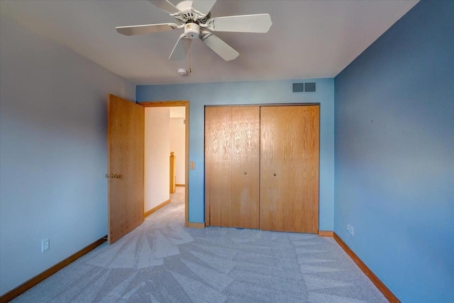 unfurnished bedroom featuring ceiling fan, light colored carpet, and a closet